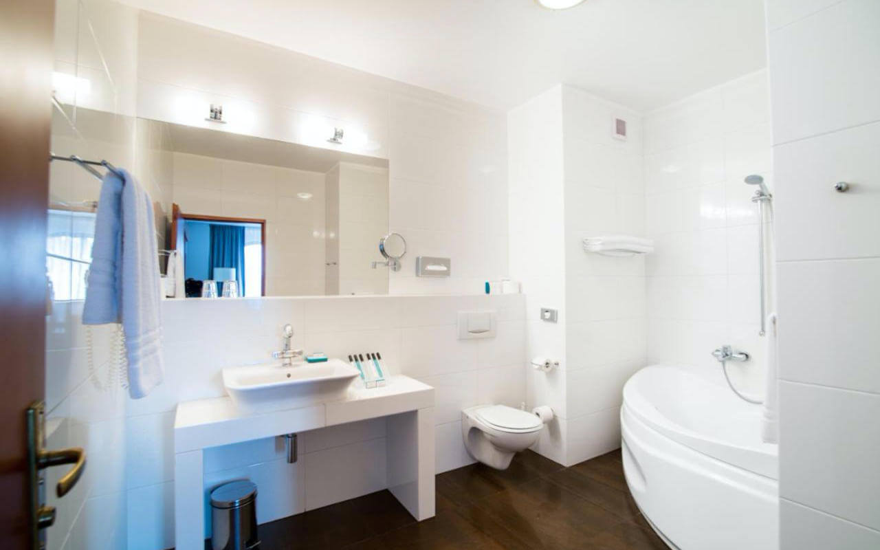 Łazienka hotelowa z dużym lustrem oraz wanną i prysznicem